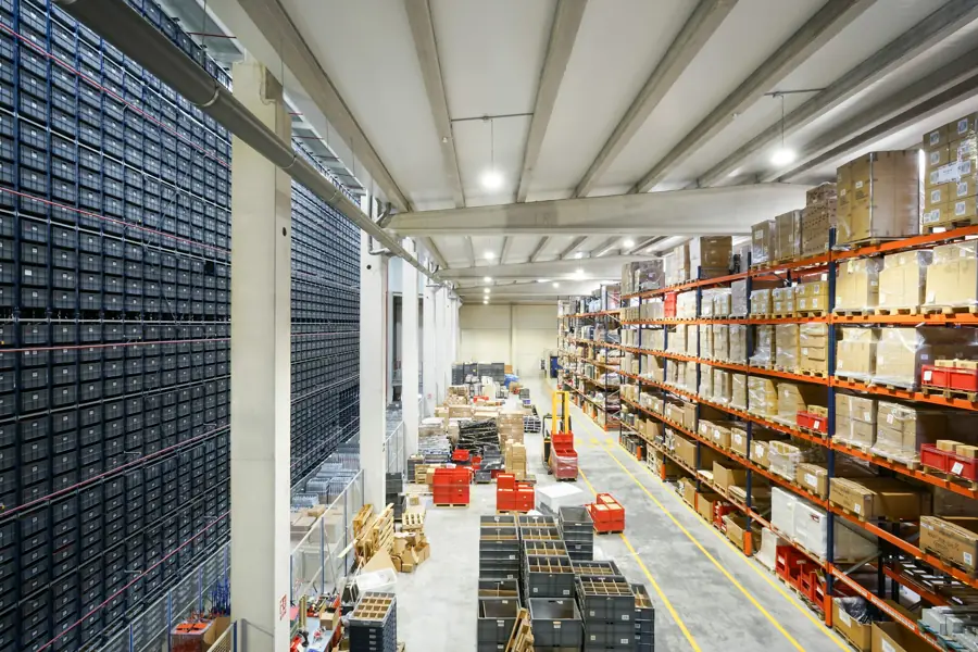 Long warehouse aisle lined with shelving and stacked boxes